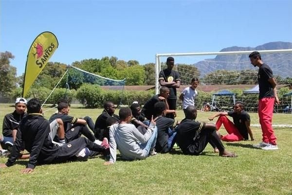 Santos FC players sitting pitch-side at a club event, Table Mountain in the background
